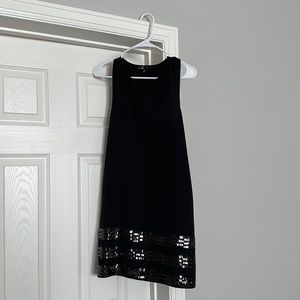Short black dress with pockets and sequins.